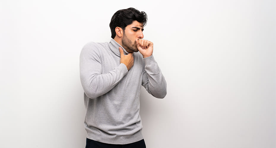 A man clutching his throat with his other hand to his mouth as he coughs