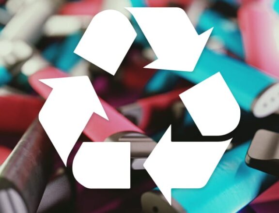 A background of many disposabel vapes with the recycling log of turning arrows in the foreground.